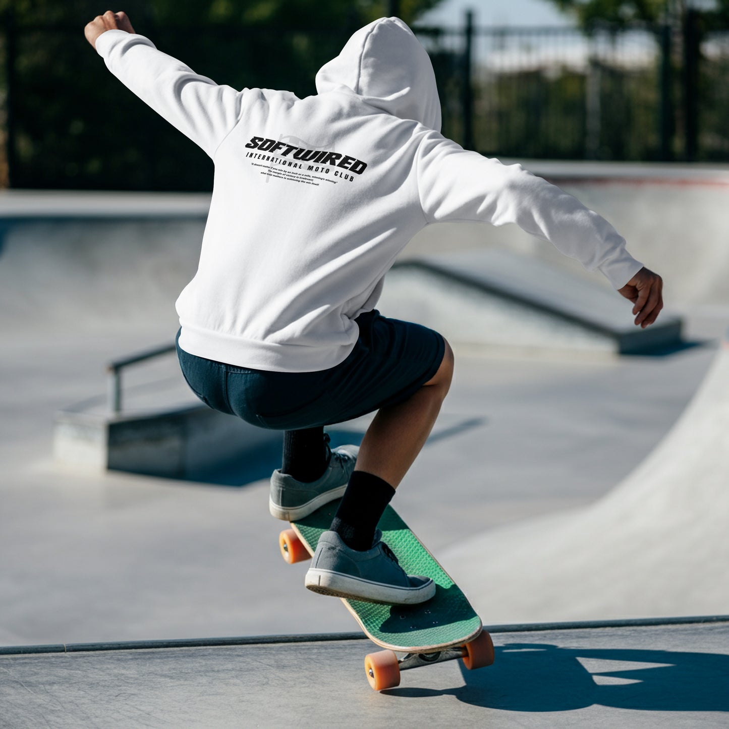 Person skateboarding at a park wearing a white hoodie with 'SOFTWIRE' branding.