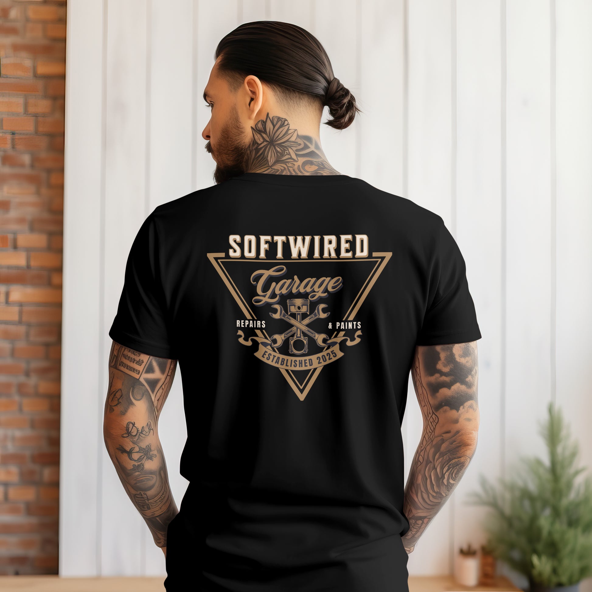 Person wearing a black t-shirt with 'Softwired Garage' design on the back, standing in front of a white wall.