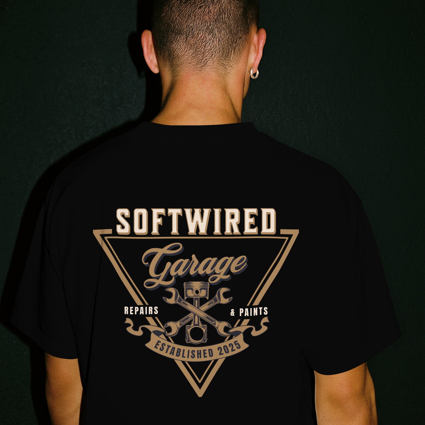 Person wearing a black t-shirt with 'Softwired Garage' design on the back against a dark background