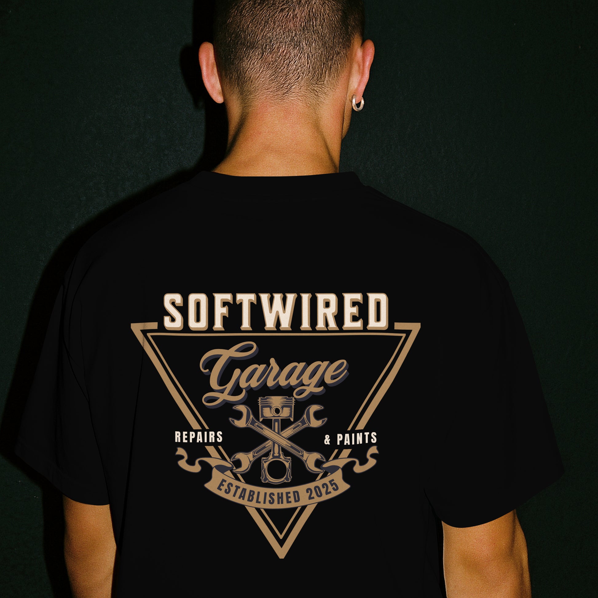 Person wearing a black t-shirt with 'Softwired Garage' design on the back against a dark background