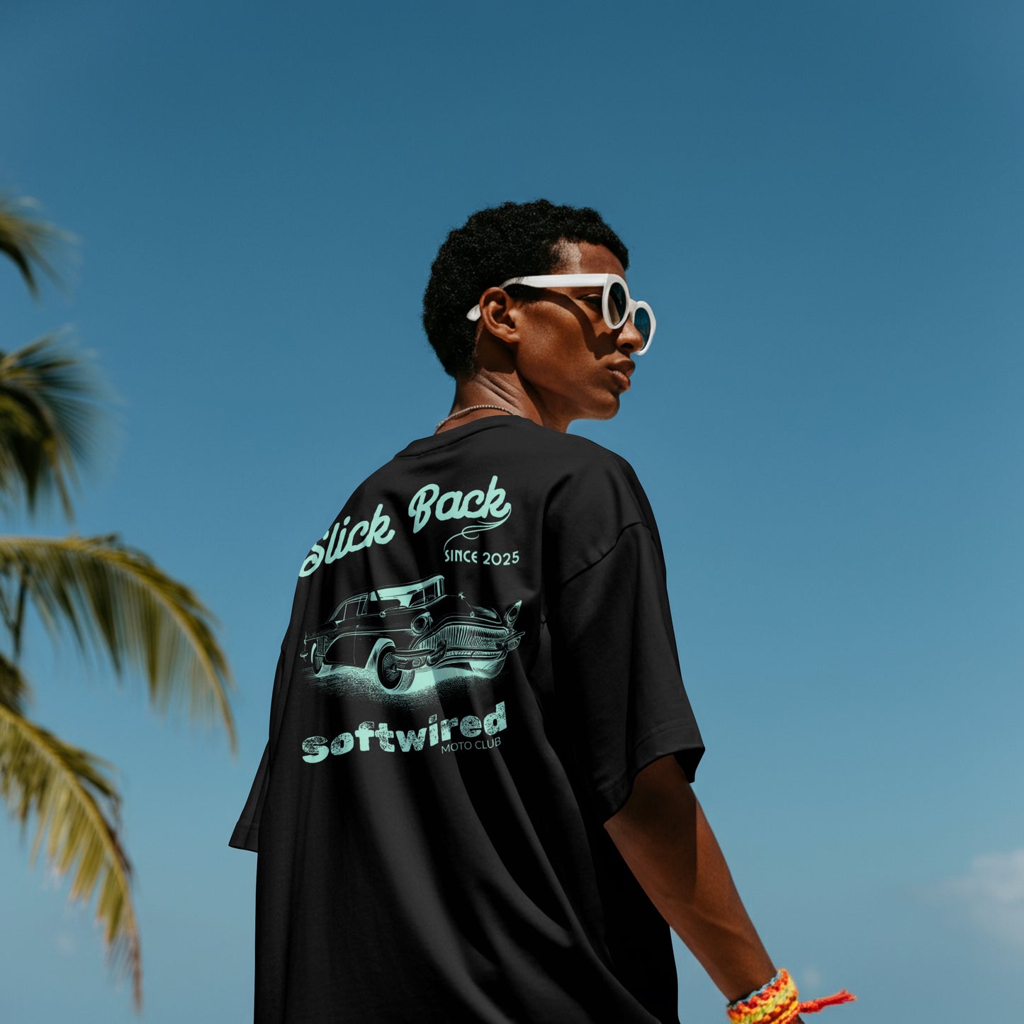 Person wearing a black t-shirt with graphics and text, standing against a clear blue sky.