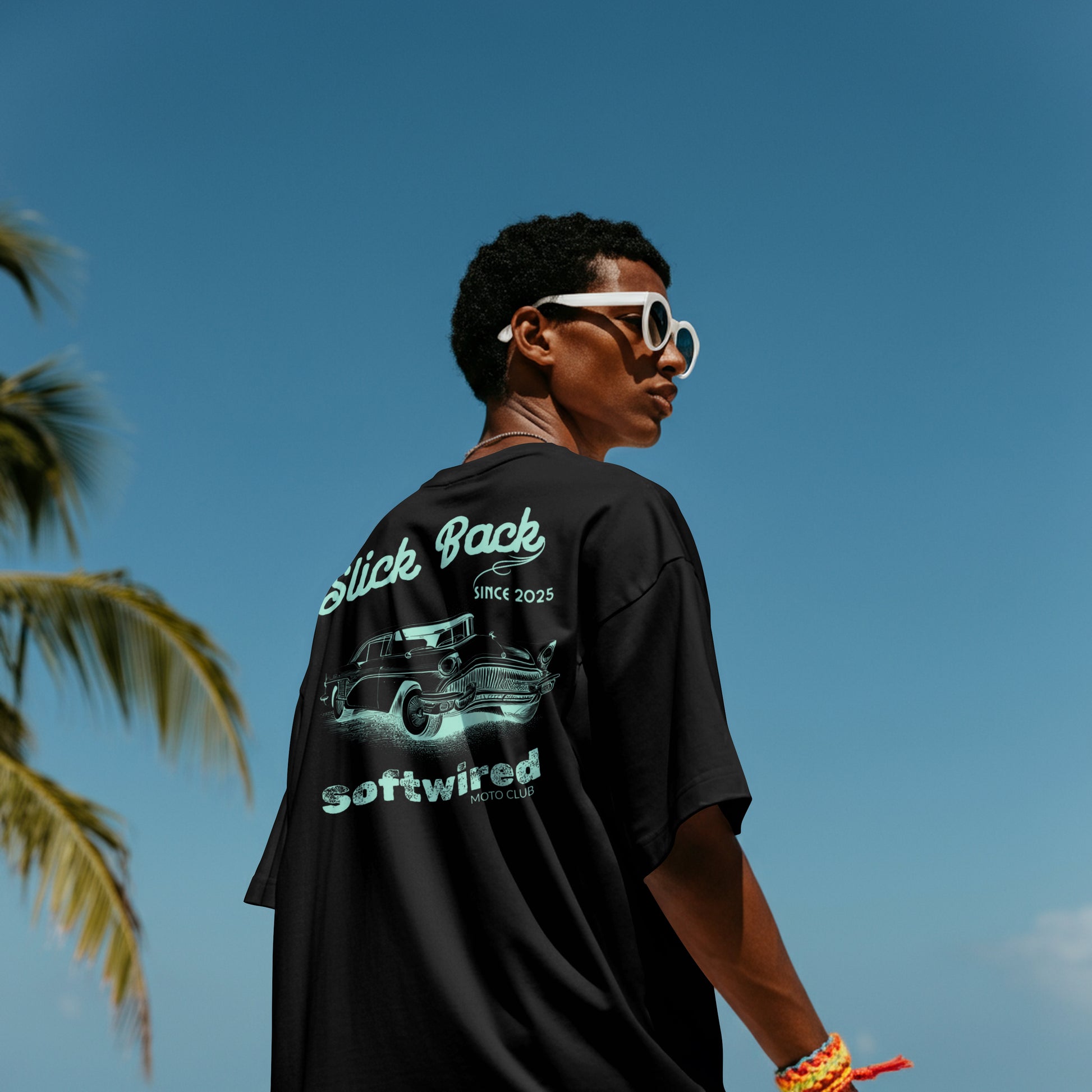 Person wearing a black t-shirt with graphics and text, standing against a clear blue sky.