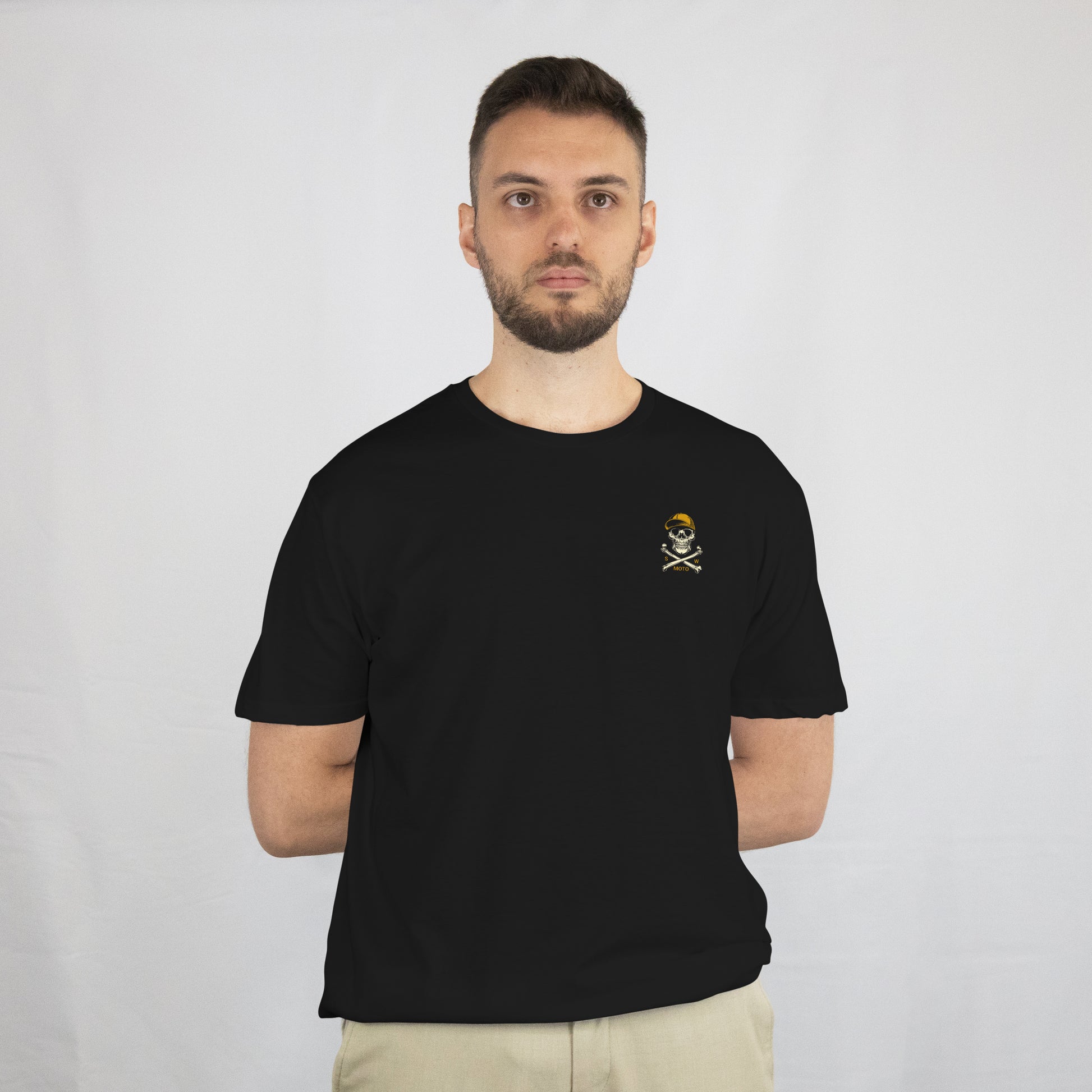 Man wearing a black t-shirt with a small logo on a plain background